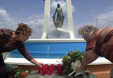 Dos mujeres colocan velas y flores en el monumento que homenajea a Rocío Jurado