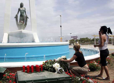 Unas mujeres colocan claveles sobre la fuente que rodea a la estatua de Rocío Jurado